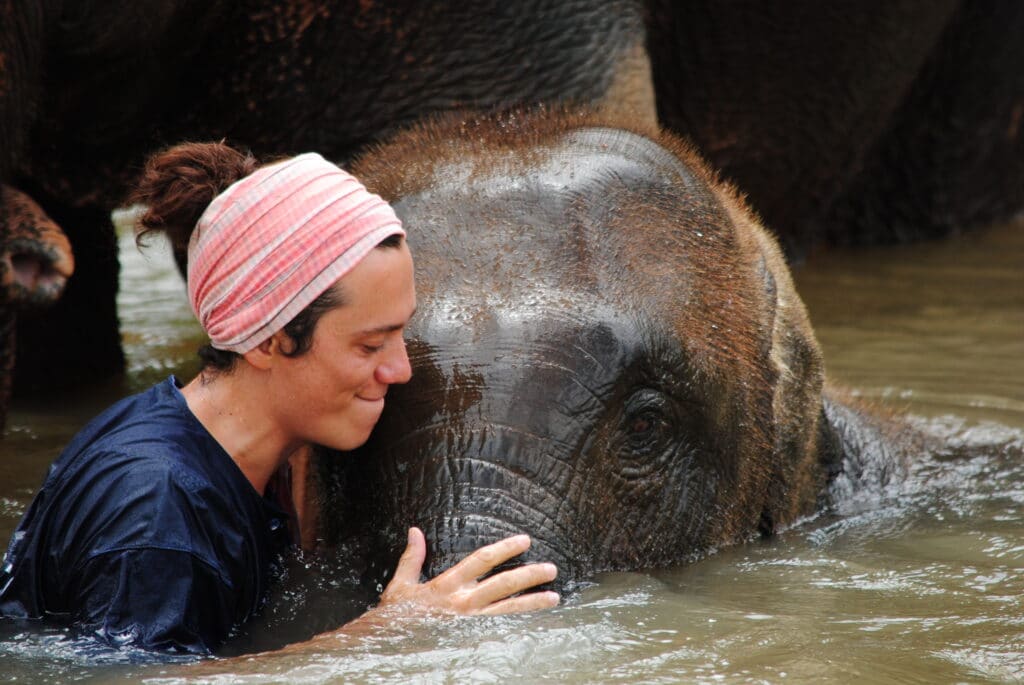 A young woman hugging an elephant in a river